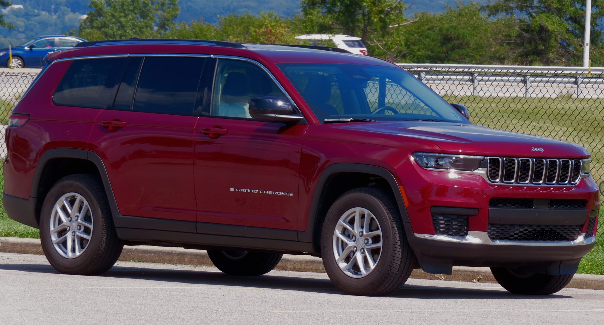 Red Jeep Grand Cherokee L parked in the sun